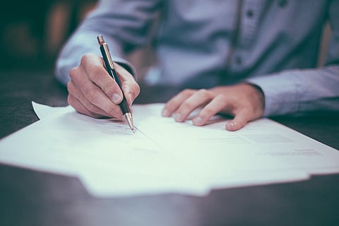 Person's hands on the table, signing documents