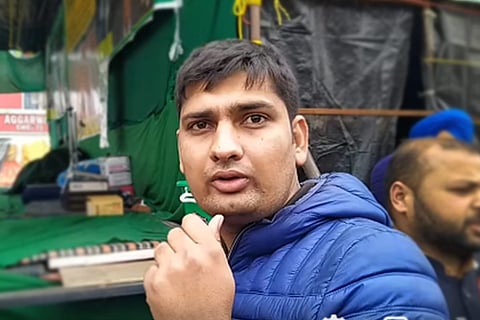 Mandeep Punia in a blue sweater speaking into a small mic