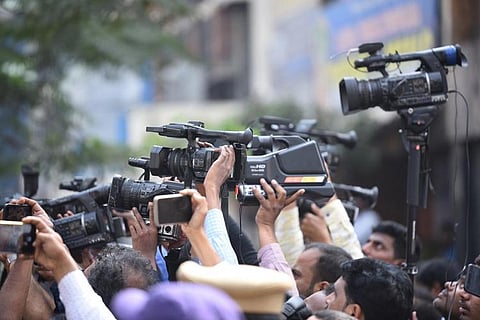 Mediapersons holding their cameras above their heads