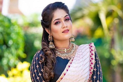 Meghana is seen in a white and blue designer saree, sporting an ethnic look.