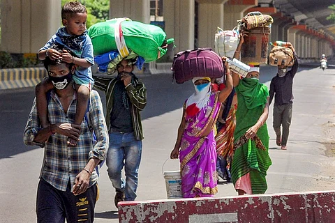 A group of informal workers along with their family walking down an empty Bengaluru street