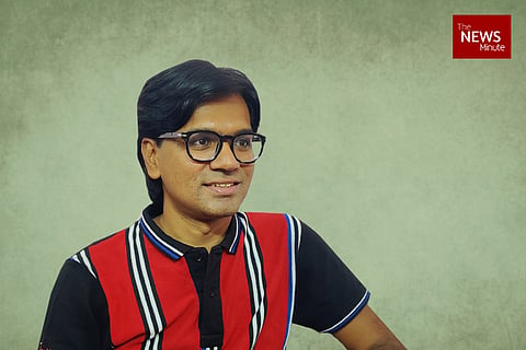 Mohammed Zubair wearing a blue and red checked polo shirt and spectacles