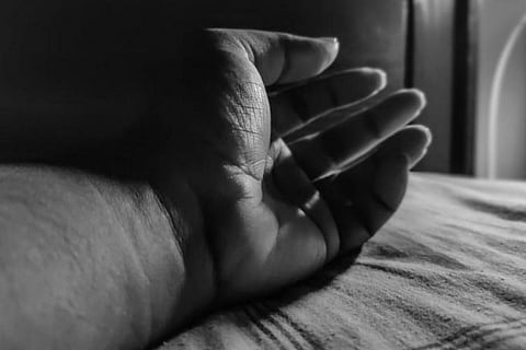 A grey image of a hand lying on bed