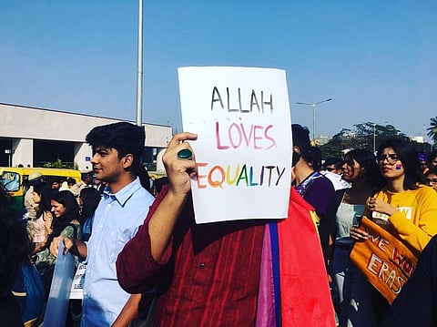 A person holding a placard saying 'Allah loves Equality'
