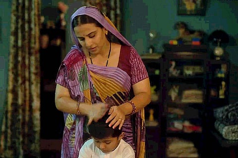 Vidya Balan in purple sari and with veil on her head placing her hand over child actor Sanika Patel in Natkhat