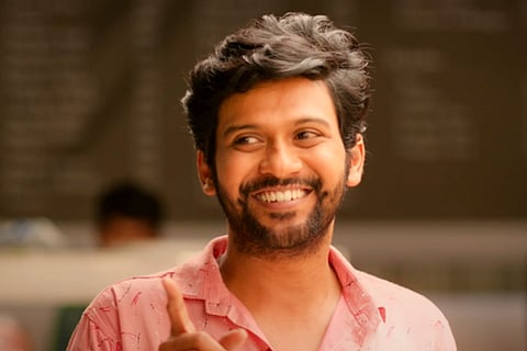 Donning a pink shirt, Naveen Polishetty is seen smiling in the screengrab from the movie 'Jathi Ratnalu'.