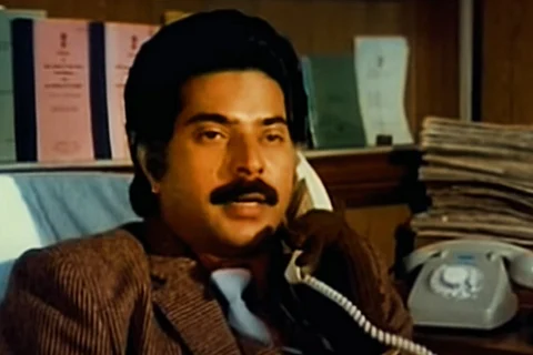 Mammootty in New Delhi movie speaking over the phone, wearing a brown shirt with tie