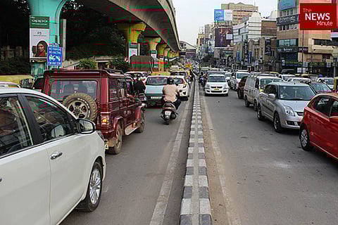 Vehicles on both sides of the road with flyover on the left and buildings on right