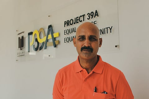 Niranaram wearing an orange T-shirt against the logo of Project39