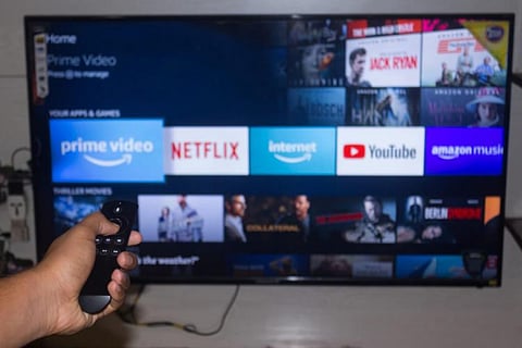 We see someone switching channels and movies loaded in an OTT platforms on the screen.