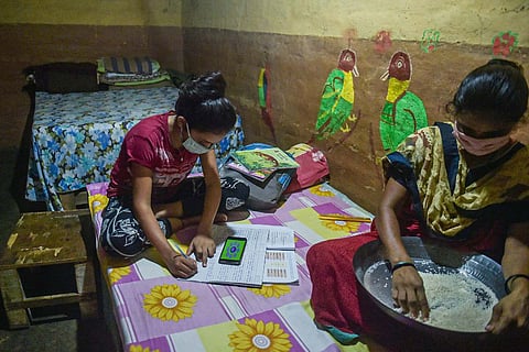 A child studying with a smartphone while her mother cooks, the ASER 2021 report found that smartphone availability at school children’s homes shot up by 30% since 2018