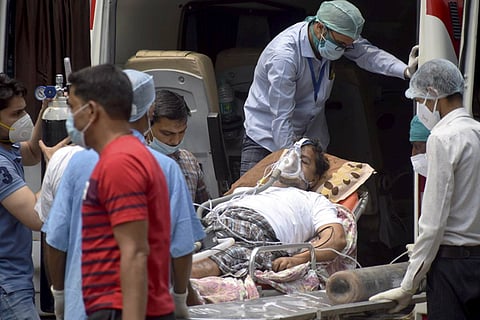 Relatives carry a COVID-19 patient on oxygen support for treatment at a hospital