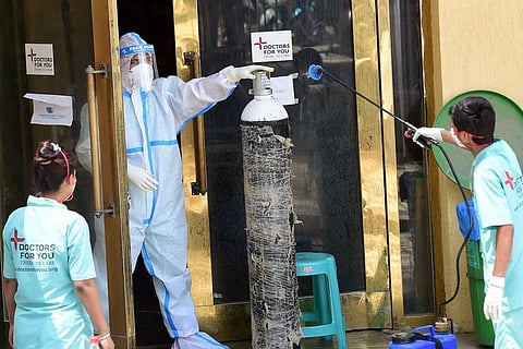Oxygen cylinder and health worker in PPE suit
