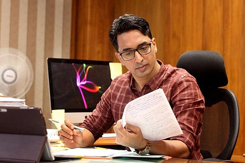 PB Nooh reading a document sitting on his chair in front of his work desk