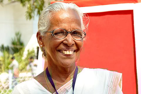 PK Medini, singer for the Left from Kerala, wearing a white saree and spectacles, smiling at the camera