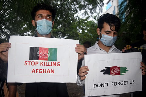 Two Afghan students holding signs protesting the Taliban