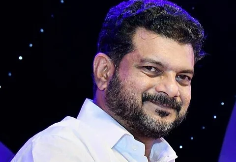A close up shot of Nilambur MLA PV Anwar. He is wearing a white shirt and smiling at the camera.