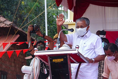 Kerala Chief Minister Pinarayi Vijayan, wearing mask, standing and speaking at a public meeting facing a mike