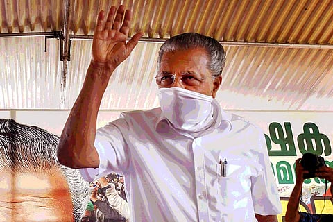 Kerala Chief Minister Pinarayi Vijayan, wearing mask, standing and waving