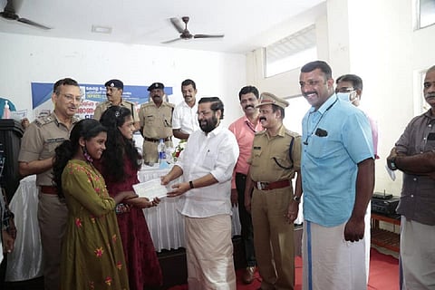 Two girls receive documents from Kadakampally Surendran
