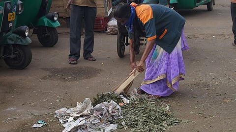 A woman sanitation worker is seen sweeping garbage off the street