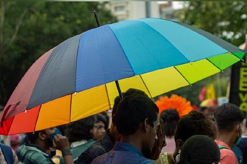 A person carrying a rainbow colored umbrella