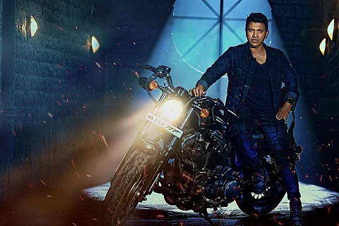 Puneeth striking a stylish pose seated on a motorbike.