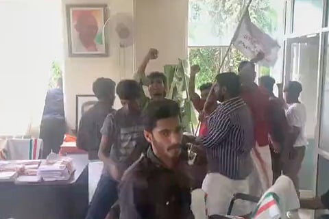 Protestors in black shirt and white dhothi vandalising the MP office in Wayanad
