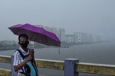 Man with an umbrella walking in rain through a bridge in Kochi