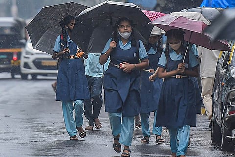 Students holding umbrellas walking in the rain