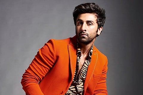 Ranbir is seen posing for the camera and is dressed in a tangerine coat and printed shirt.