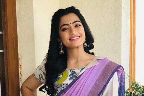 Rashmika Mandanna is seen in a lavender-coloured saree, smiling for camera.