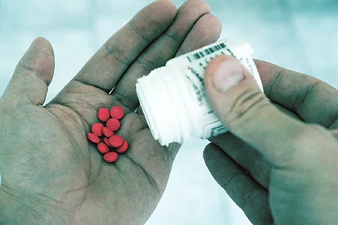 A person with red colored pills in hand