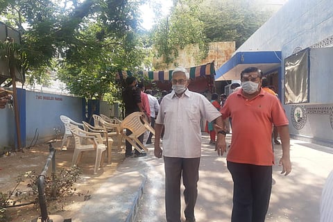 There is a serpentine row of plastic chairs with senior citizens and their attendants seated, devoid of physical distancing, waiting for the queue to move.