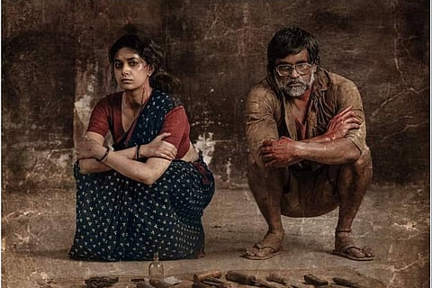 Keerthy Suresh and Selvaraghavan squatting in the mud with weapons