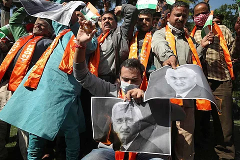 Protesters wearing saffron scarves holding up posters of Salman Khurshid in protest