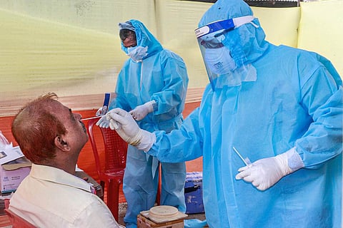 Medical professional in PPE kit collects samples of people