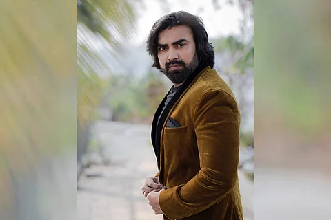 Sandeep Nahar standing sideways facing the camera in a brown blazer