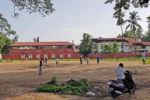 Children playing at the Santa Cruz ground in Fort Kochi as a man on a parked two-wheeler watches in the foreground