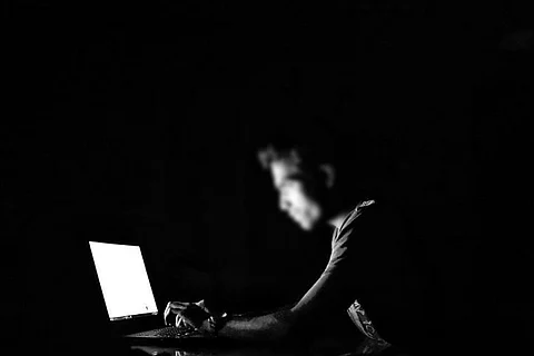 A representative image of a man on a computer in a dark room