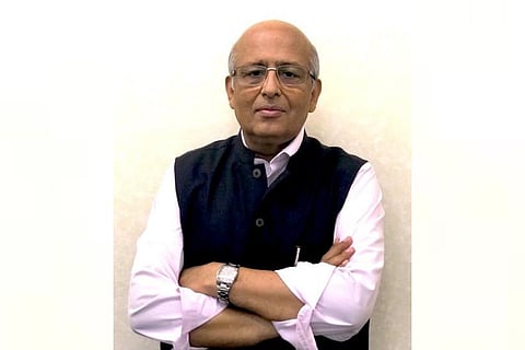 Virologist Shahid Jameel wearing a white shirt and a black Nehru jacket and looking into the camera with his arms crossed.