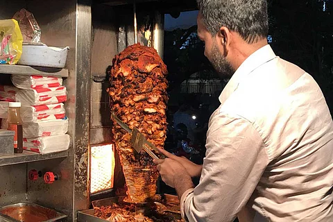 A person cutting meat from a rotisserie