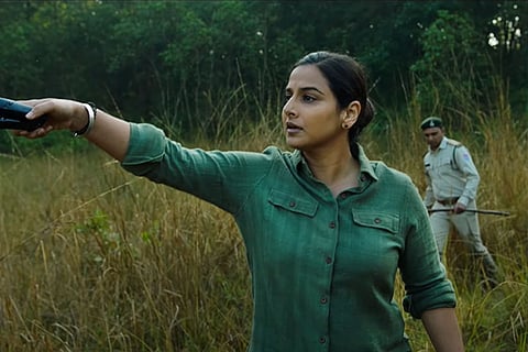 Vidya Balan in a green shirt standing in fields in a scene from Sherni