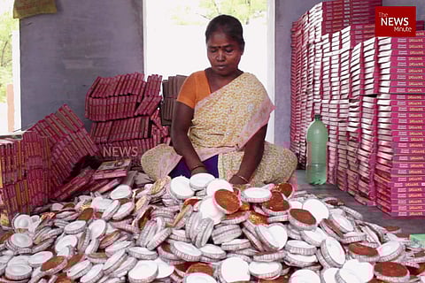 A woman fireworks worker sits before a pile of crackers at a factory in Sivakasi