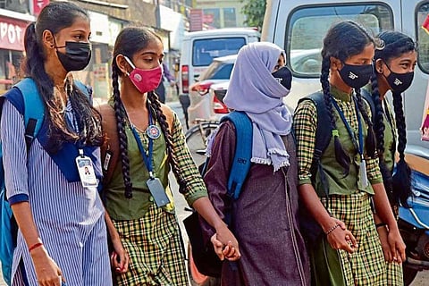 Students in uniform holding hands with a hijab wearing student