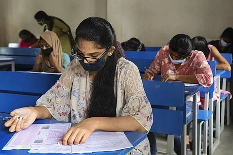 TS Inter Results 2021: Students sitting at individual benches while wearing masks, writing an exam