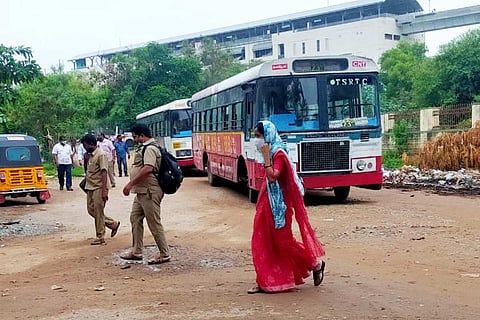 A woman conductor dressed in a saree walking inside a TSRTC depot