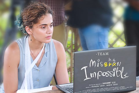 Taapsee with her hand in a sling and looking at a laptop.