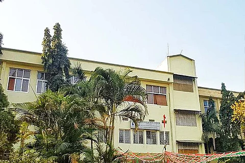 A pale green building in the TISS Hyderabad campus with trees in the foreground