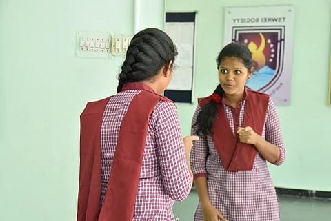 A young girl student of Telangana Social Welfare Residential Educational Institutions Society speaking into a mirror